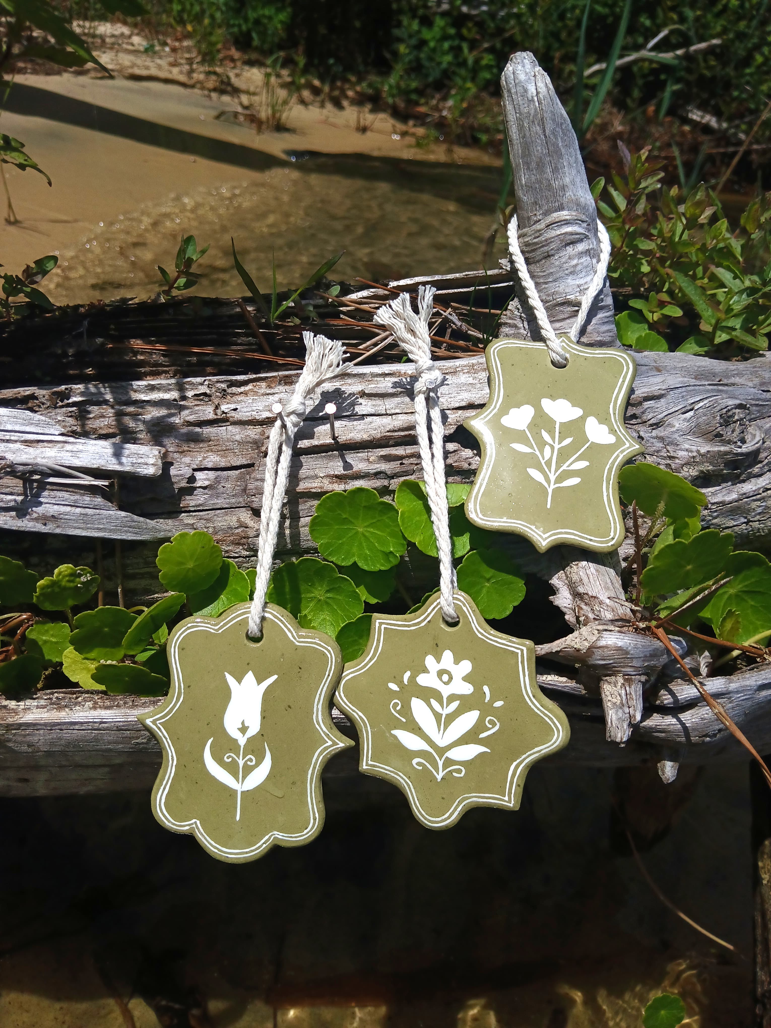 Trio floral tulipe, fleur folk et branche fleurie en argile kaki peinte en blanc, suspendu à du bois flotté