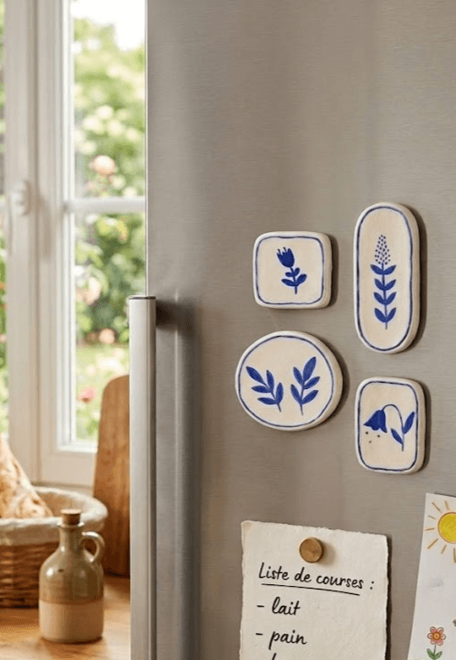 Lot de quatre magnets en argile blanche peints en bleu, sur un réfrigérateur